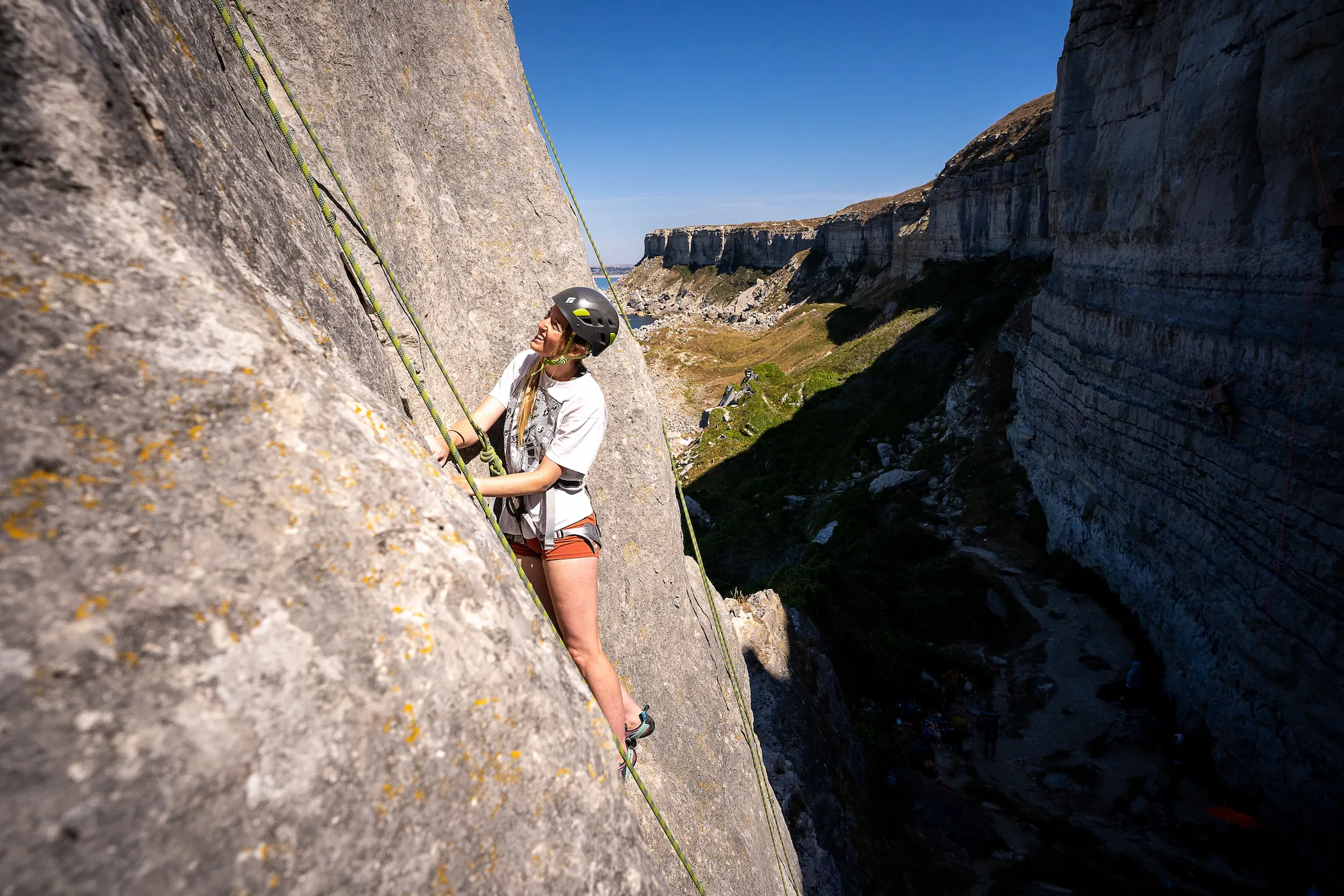 Ella is half way up her climbing route, resting on a small ledge as she looks at the next section.